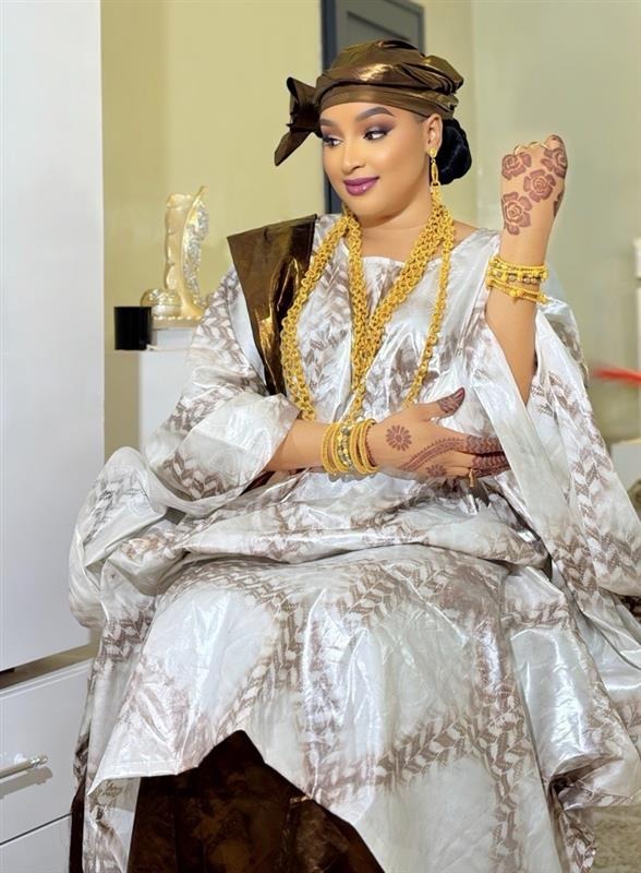 Femme assise en boubou brodé avec bijoux dorés, studio Doucshoot